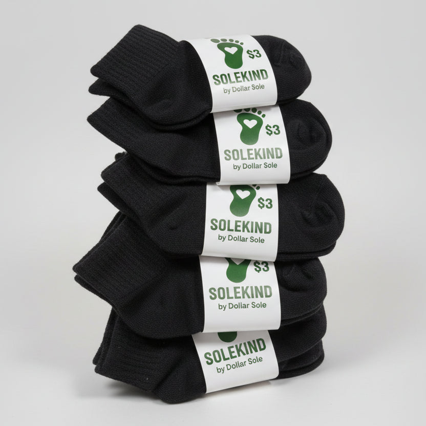 Five pairs of black socks with 'Solekind' labels on a gray surface