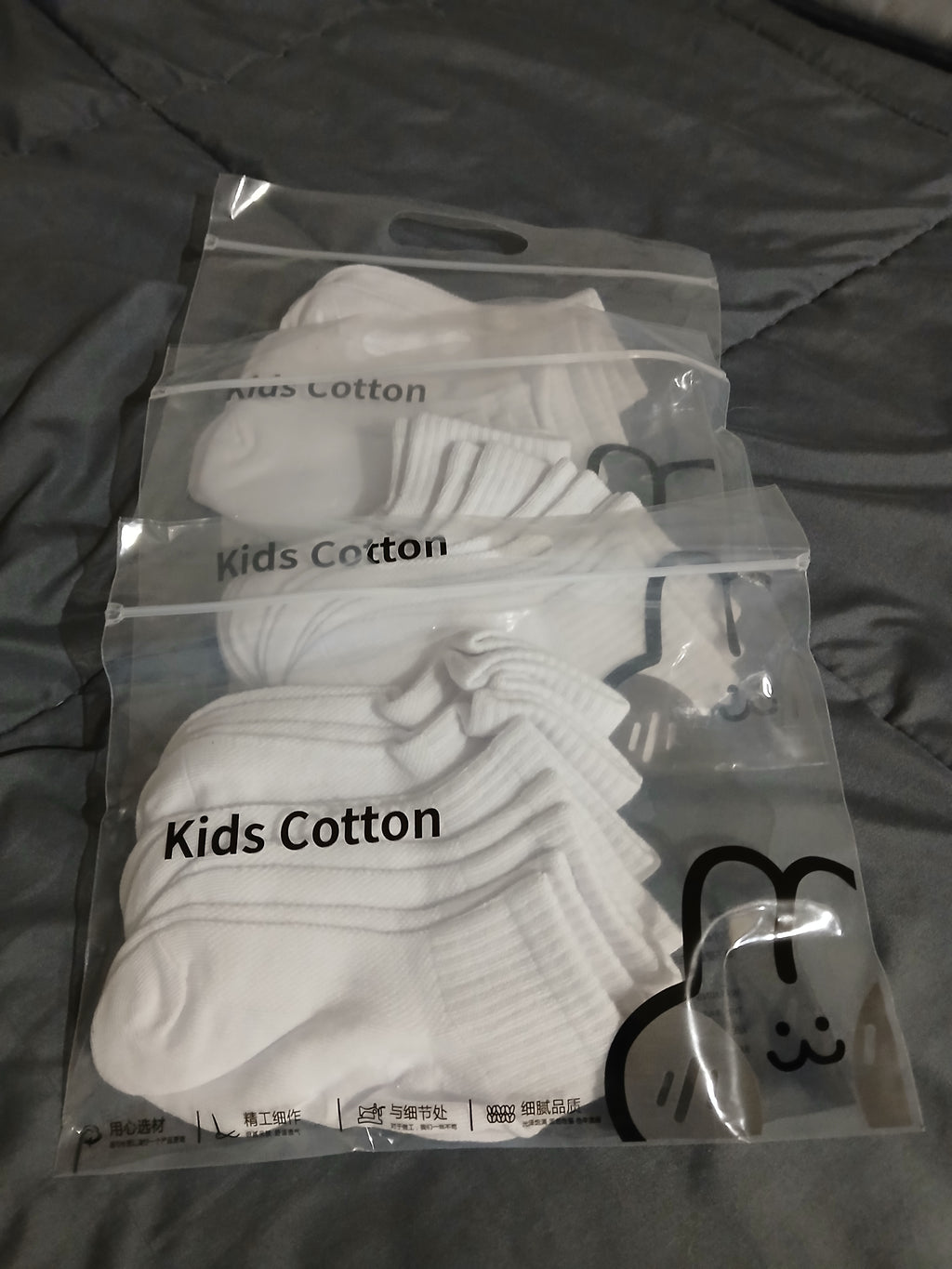 Pack of white socks with 'Kids Cotton' label on a dark background